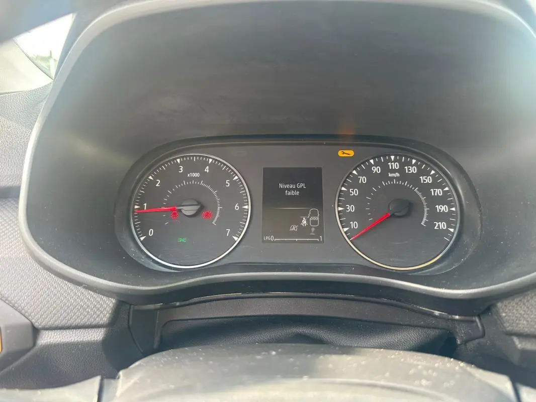 Vue rapprochée du tableau de bord de la Dacia Sandero bleu foncé montrant l'indicateur de niveau GPL faible.