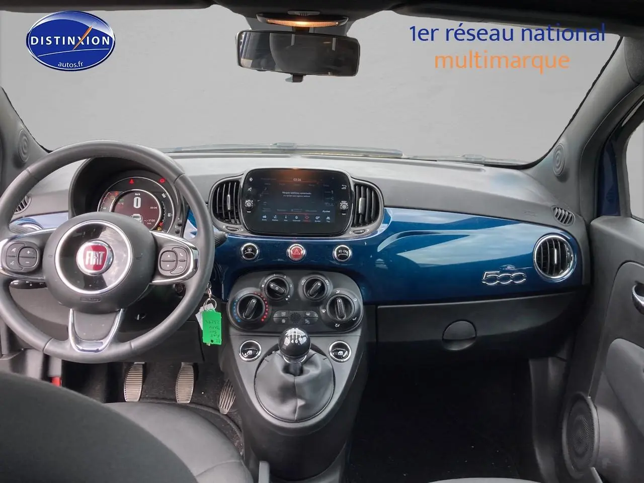 Vue intérieure avant du tableau de bord bleu brillant de la Fiat 500 2023 avec volant multifonction et écran tactile central.