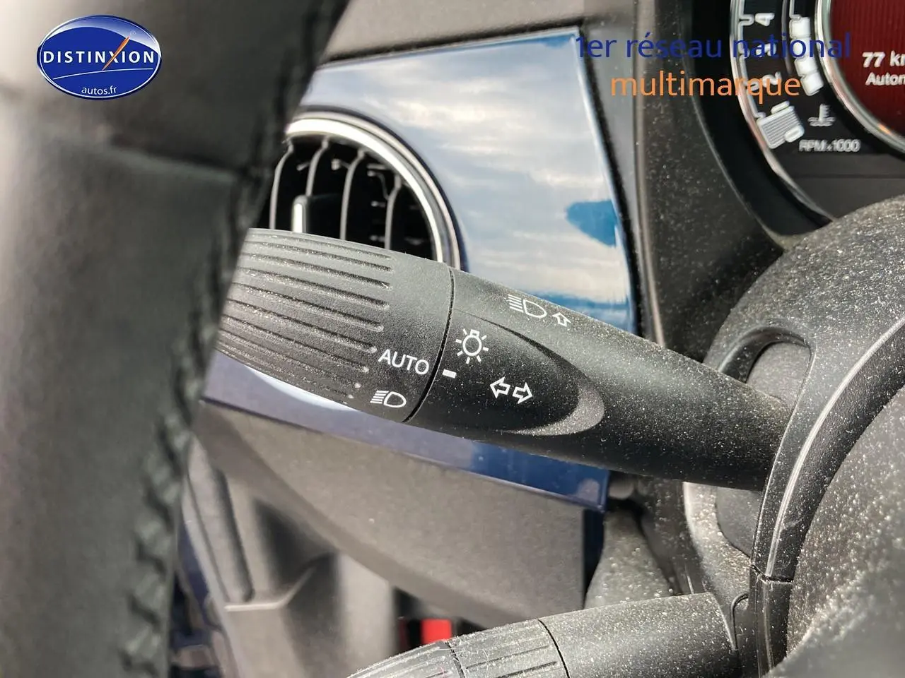 Détail du commodo d’éclairage noir sur fond bleu brillant du tableau de bord d’une FIAT 500 2023.