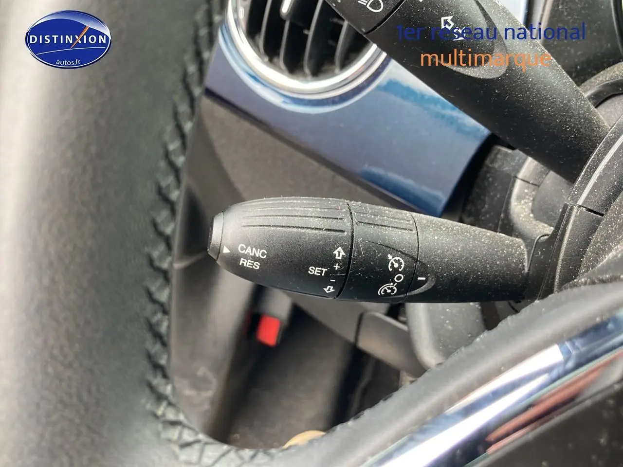 Gros plan sur la commande de régulateur de vitesse côté gauche du volant d’une Fiat 500 bleu 2023.