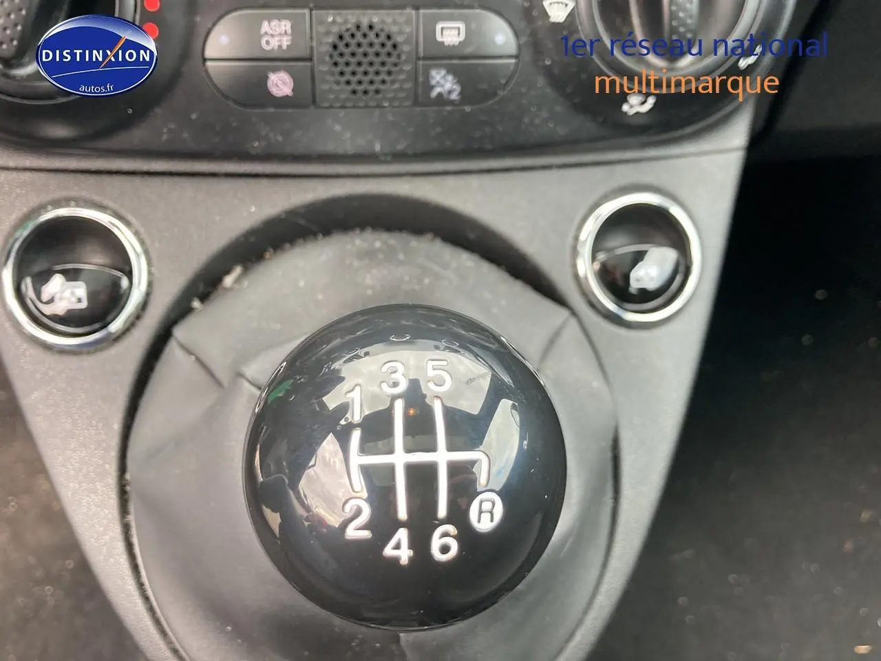 Gros plan sur le levier de vitesses manuel noir de la FIAT 500 bleu, avec console centrale en arrière-plan.