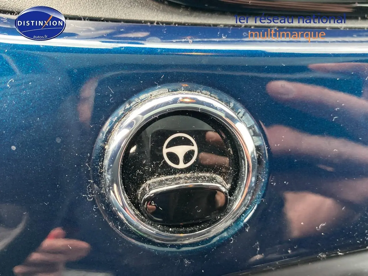 Gros plan sur la poignée de porte chromée d’une FIAT 500 bleue 2023 avec symbole volant gravé.