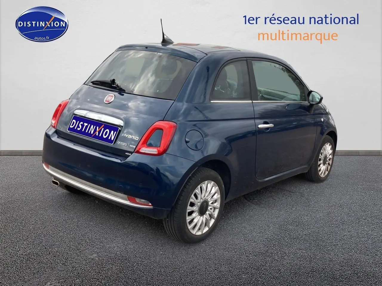 Vue 3/4 arrière droite d'une Fiat 500 bleue 2023 avec jantes alu et toit panoramique en verre.