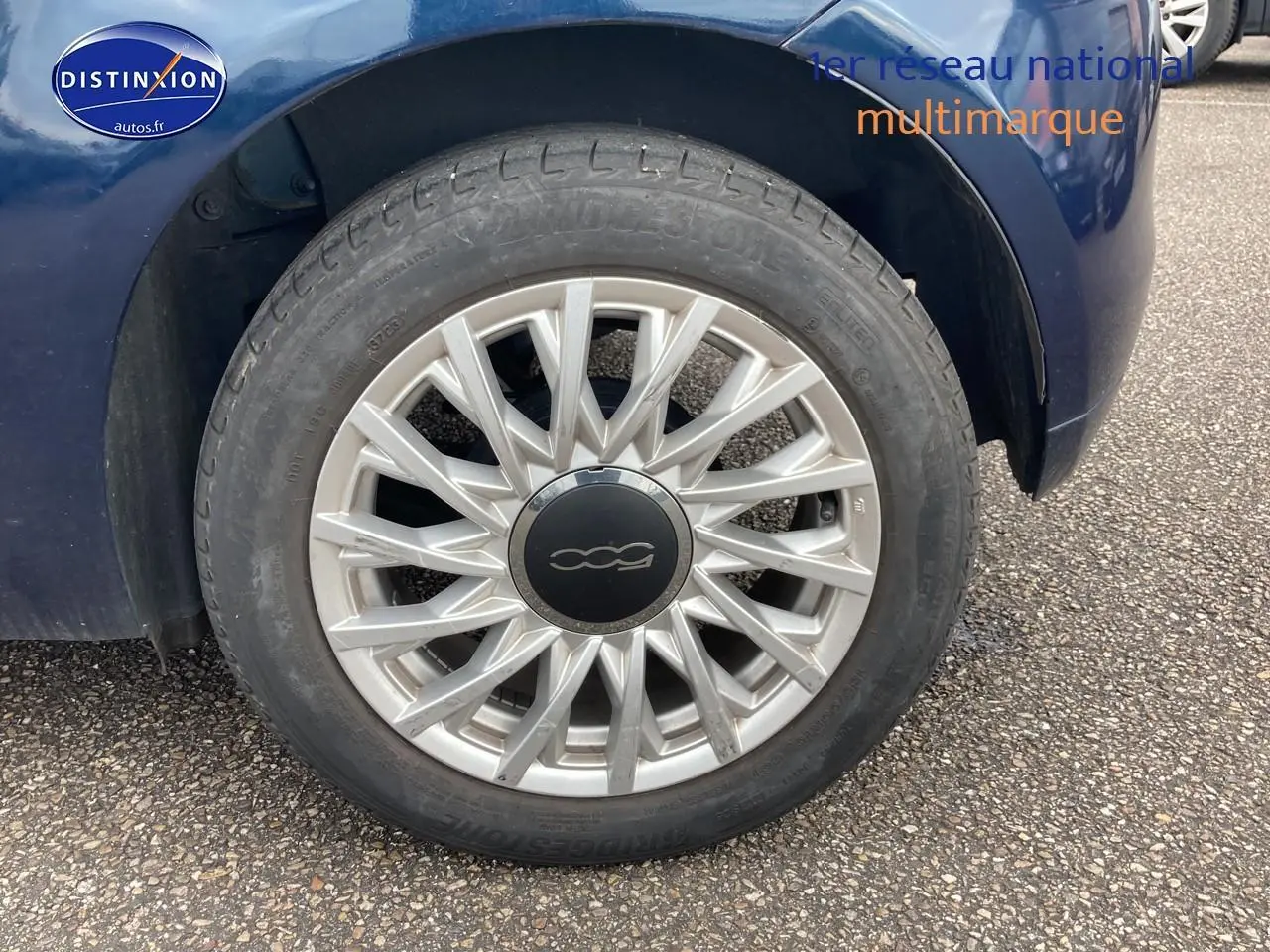 Gros plan sur la roue avant droite de la FIAT 500 bleu 1.0 70 bsg dolcevita avec jante alu multibranches.