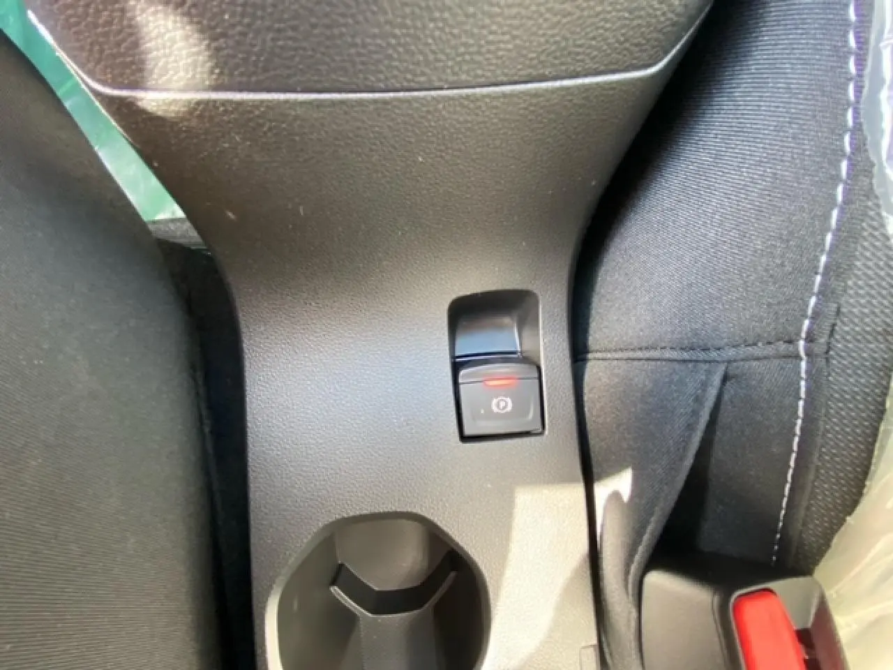 Vue rapprochée du frein à main électrique et porte-gobelet central sur la console d’une Dacia Logan gris 2022.