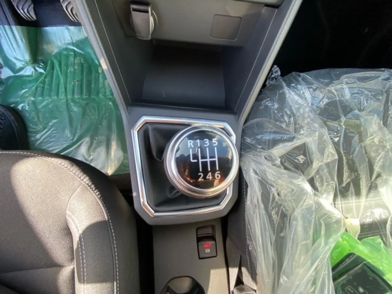 Vue plongeante sur la boîte manuelle de la Dacia Logan gris 2022, avec siège passager protégé par un film plastique.