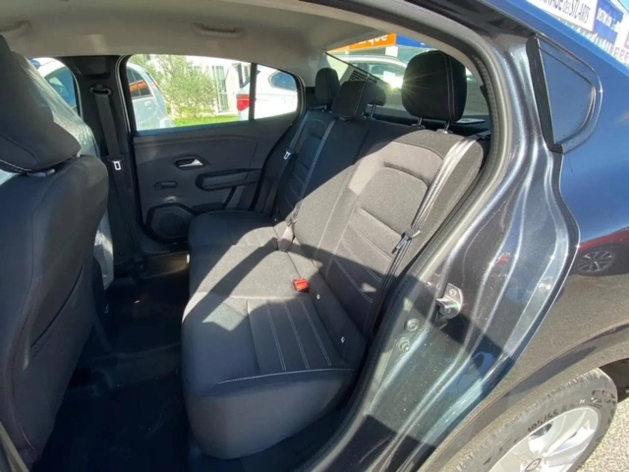 Vue intérieure côté arrière droit de la Dacia Logan gris 2022, montrant les sièges arrière en tissu noir.