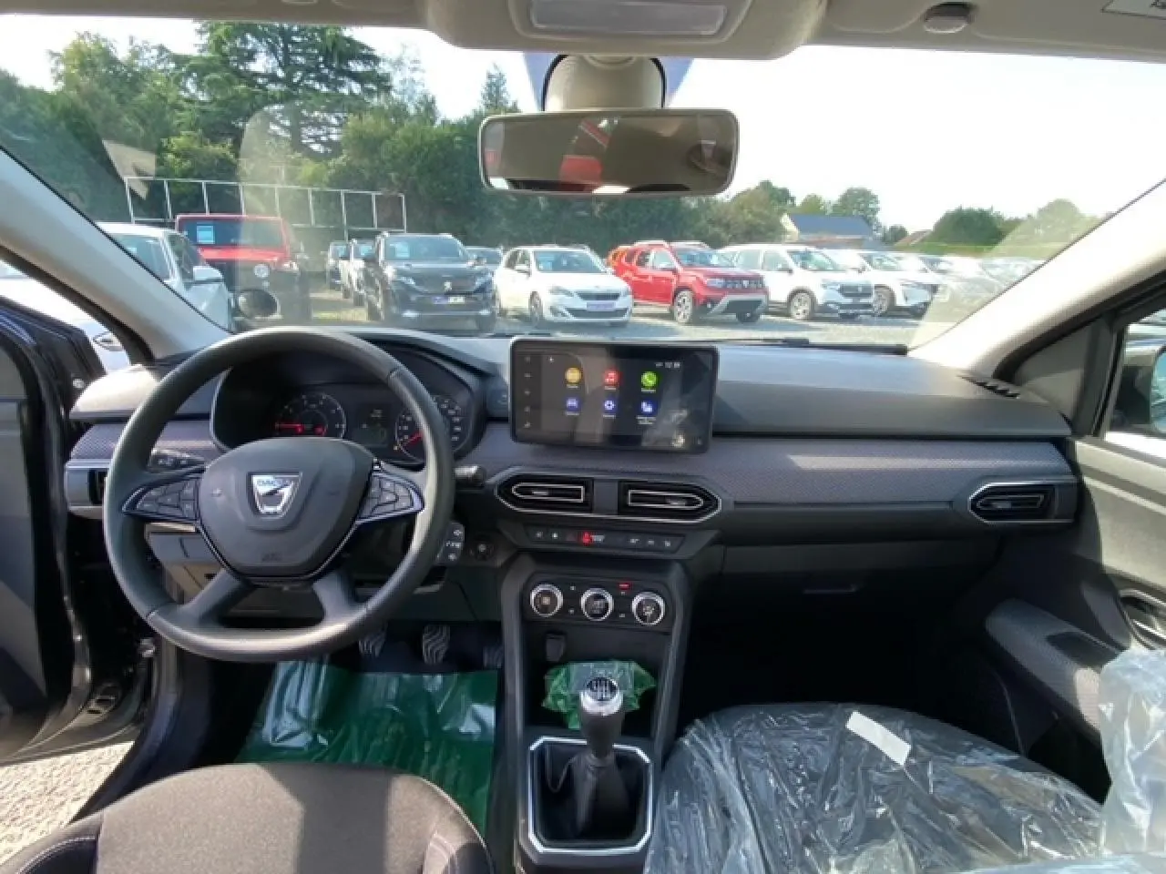 Vue intérieure avant de la Dacia Logan 2022, tableau de bord gris avec écran tactile Media Nav et boîte manuelle.