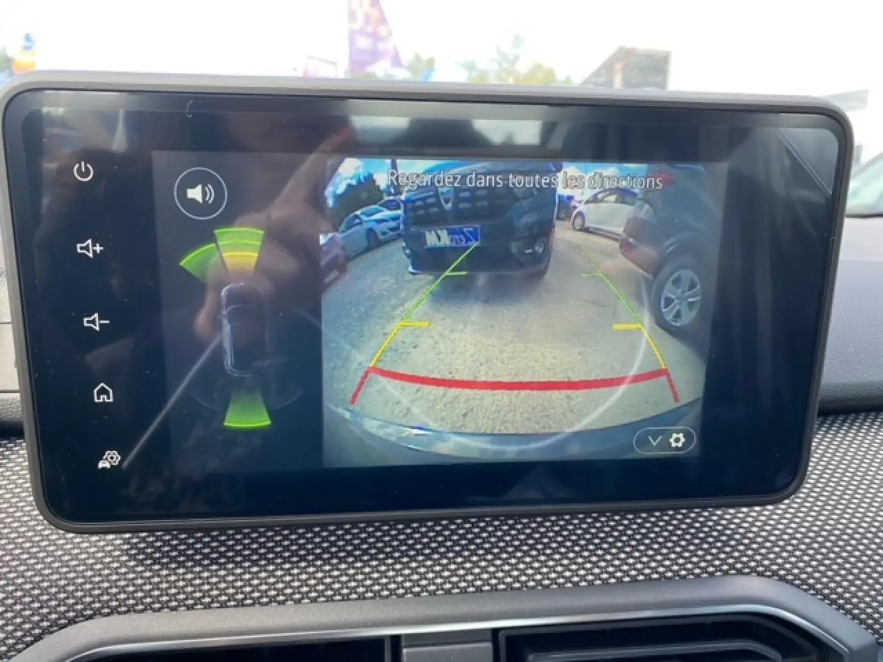 Écran tactile Media Nav montrant la caméra de recul active avec vue arrière et alertes radar sur Dacia Logan gris.