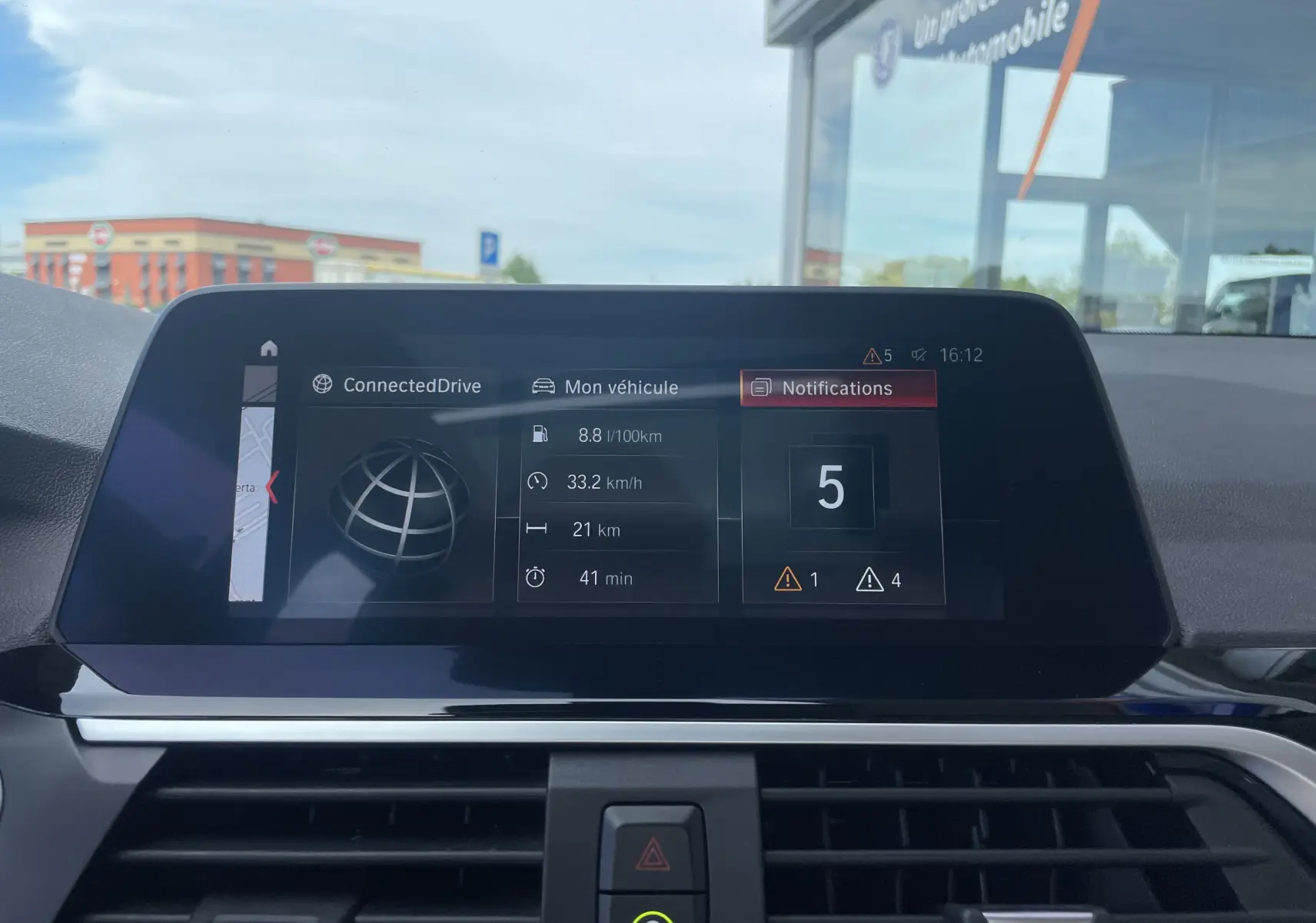 Écran central du tableau de bord de la BMW X3 noir (G01) affichant la consommation et les notifications, vue intérieure frontale.