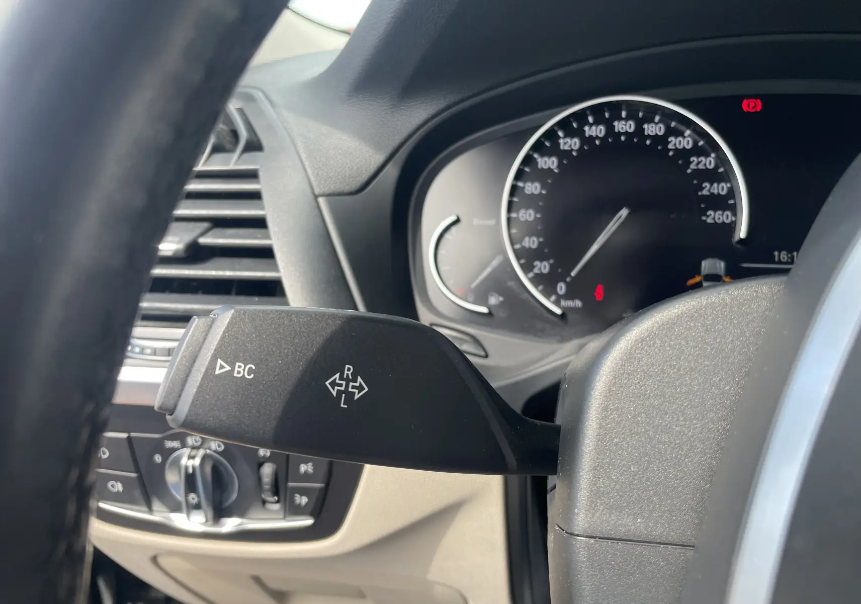 Gros plan sur la manette de clignotant côté gauche dans l’habitacle beige d’un BMW X3 noir (G01) 2021.