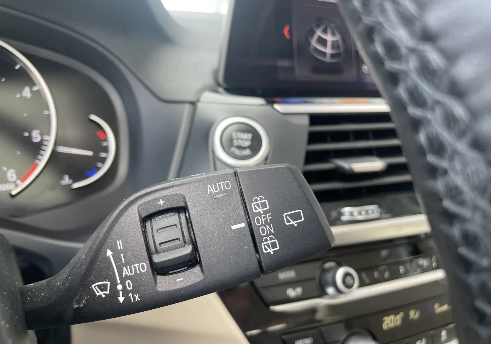 Gros plan sur la commande d’essuie-glace à gauche du volant dans l’habitacle beige d’un BMW X3 noir 2021.