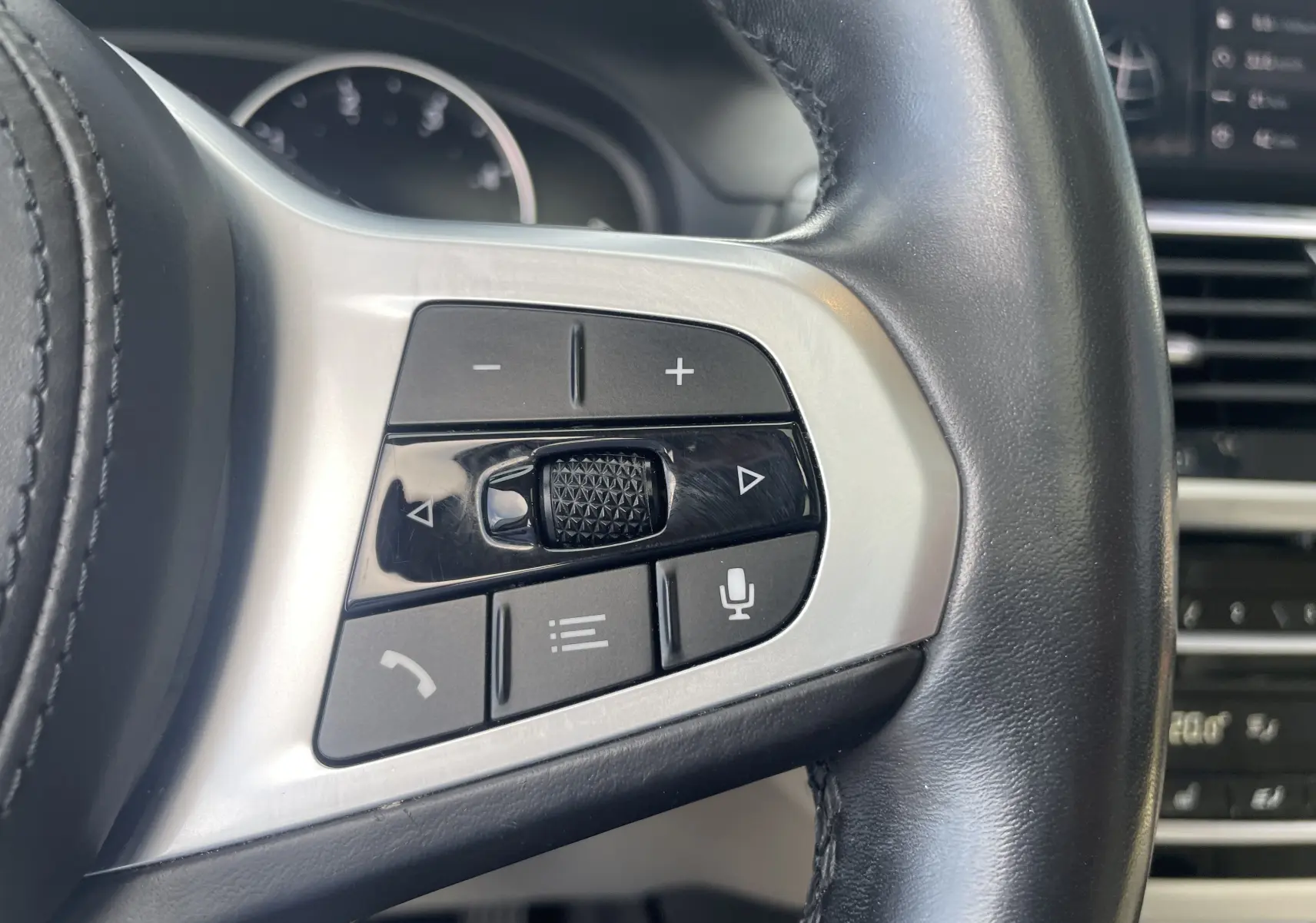 Gros plan sur les commandes multifonctions en noir et argent du volant cuir du BMW X3 G01 2021.