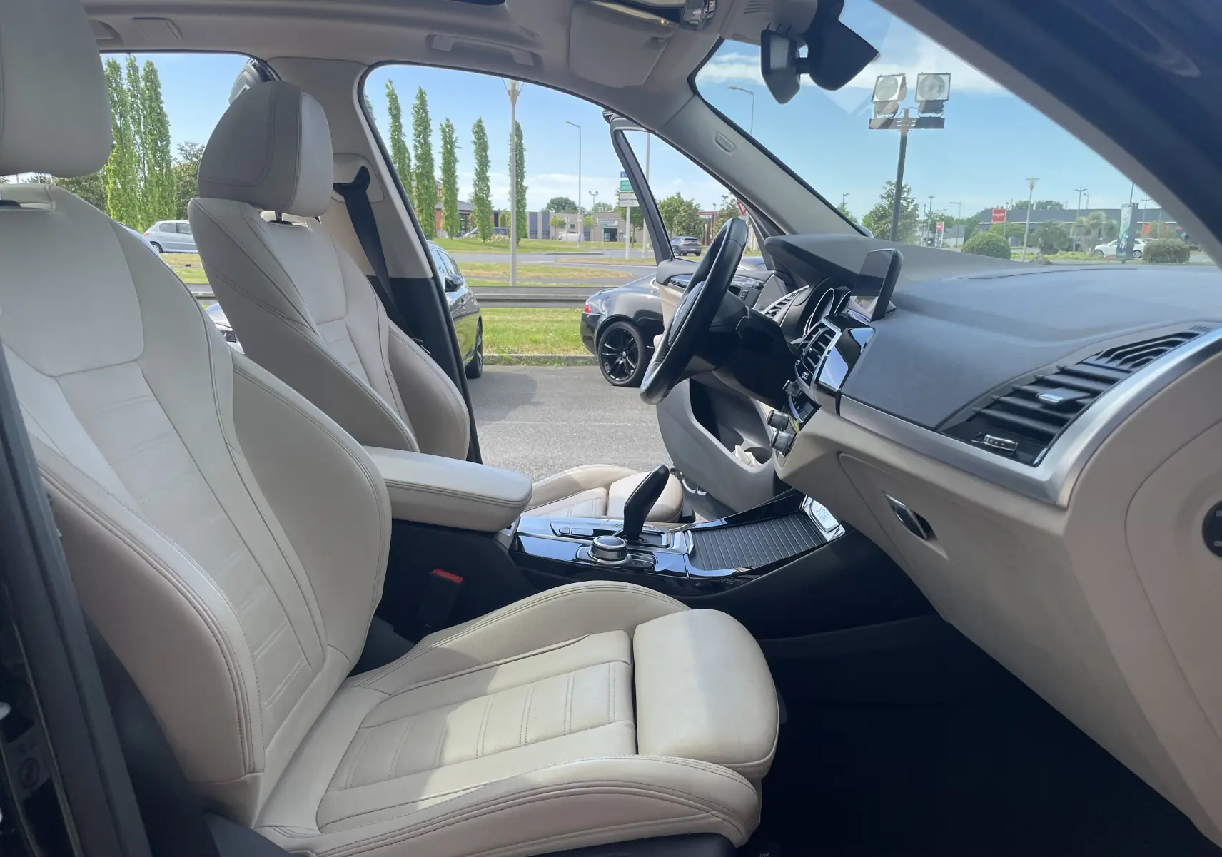 Vue intérieure côté gauche de la BMW X3 2021 avec sièges en cuir beige et tableau de bord noir élégant.