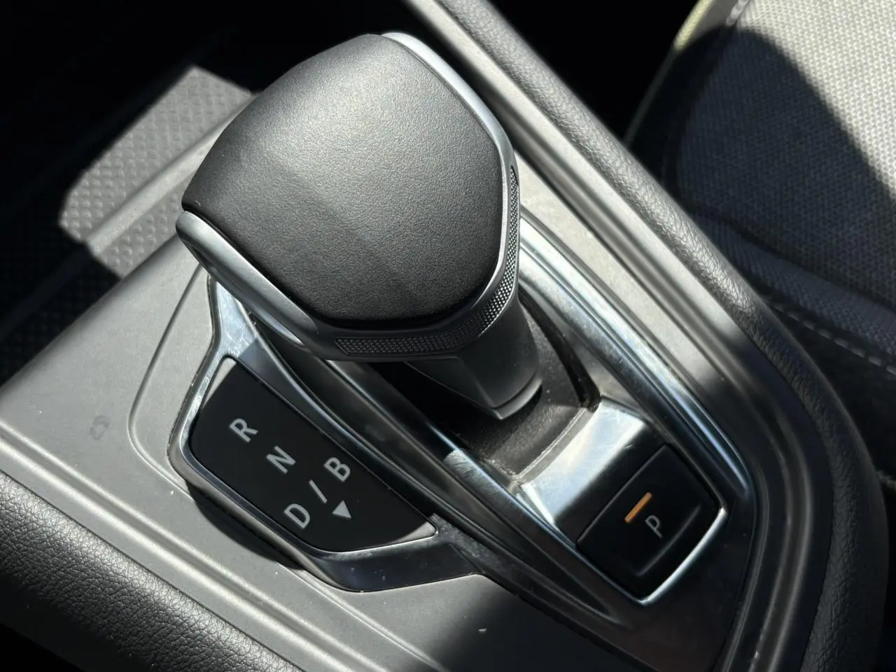 Le levier de vitesses automatique noir de la Renault SYMBIOZ E-Tech vu en gros plan dans la console centrale.