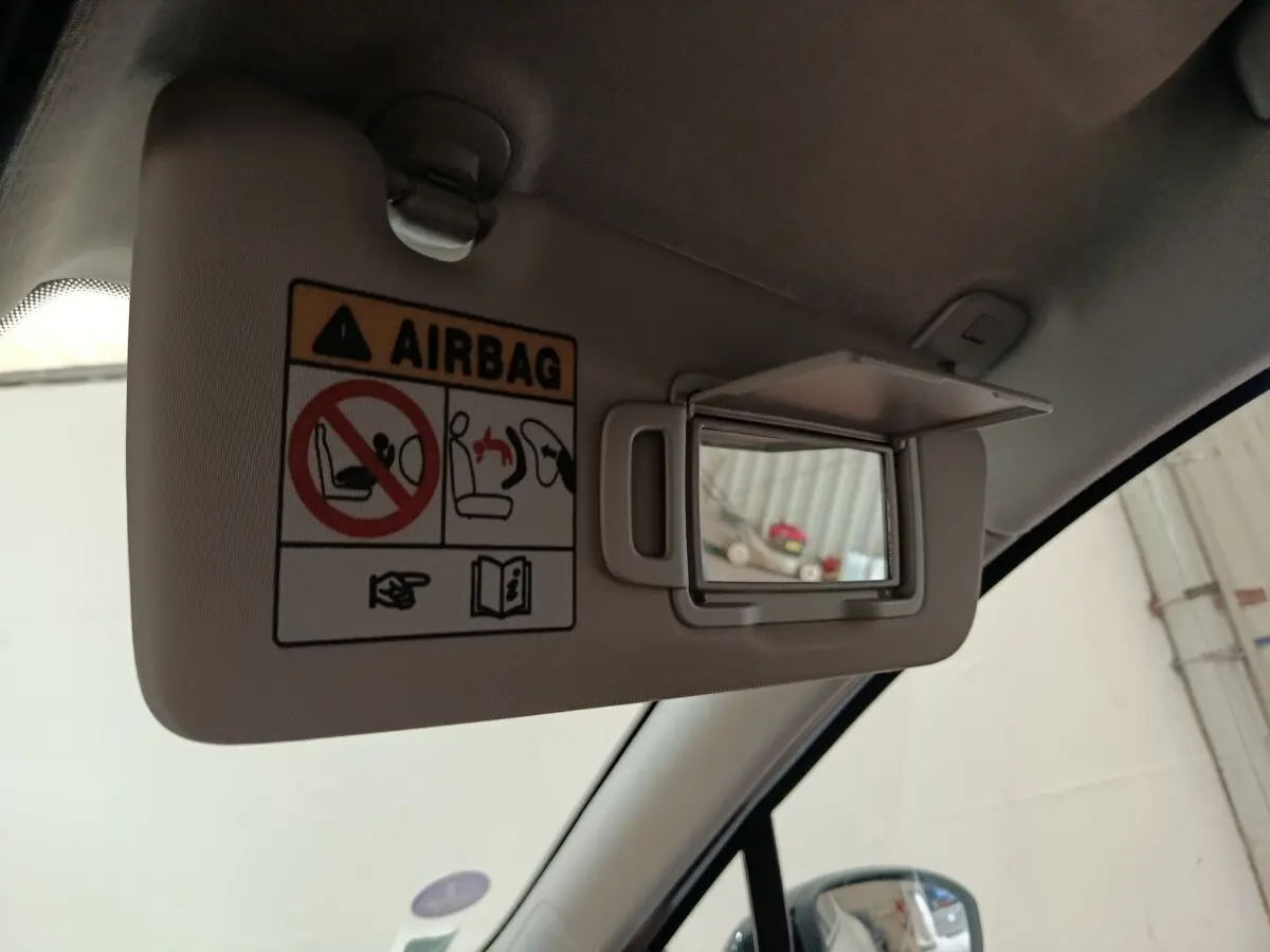 Détail intérieur du pare-soleil côté conducteur avec miroir et avertissement airbag dans une Renault Clio blanche.