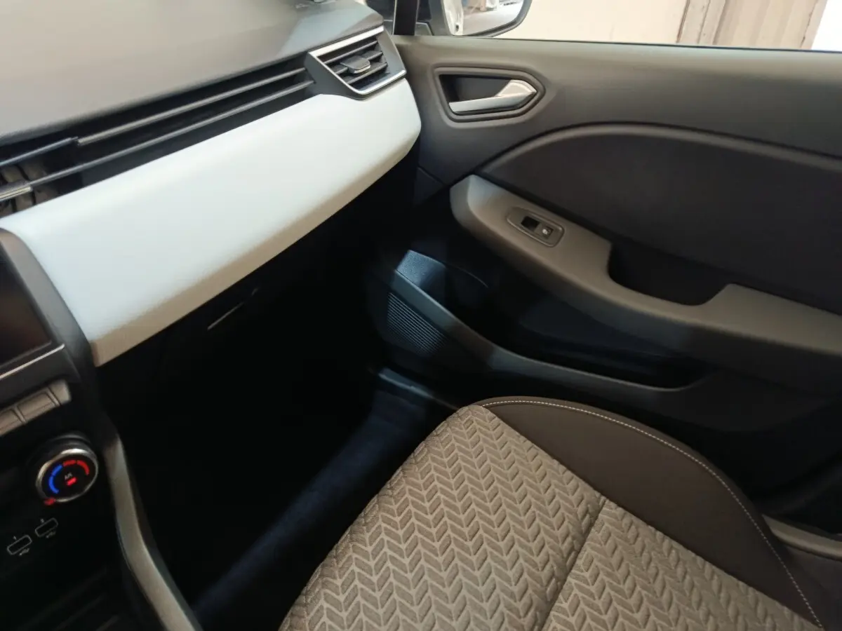 Vue intérieure côté passager avant de la Renault Clio Evolution TCe 90 2023, siège tissu gris et tableau de bord clair.