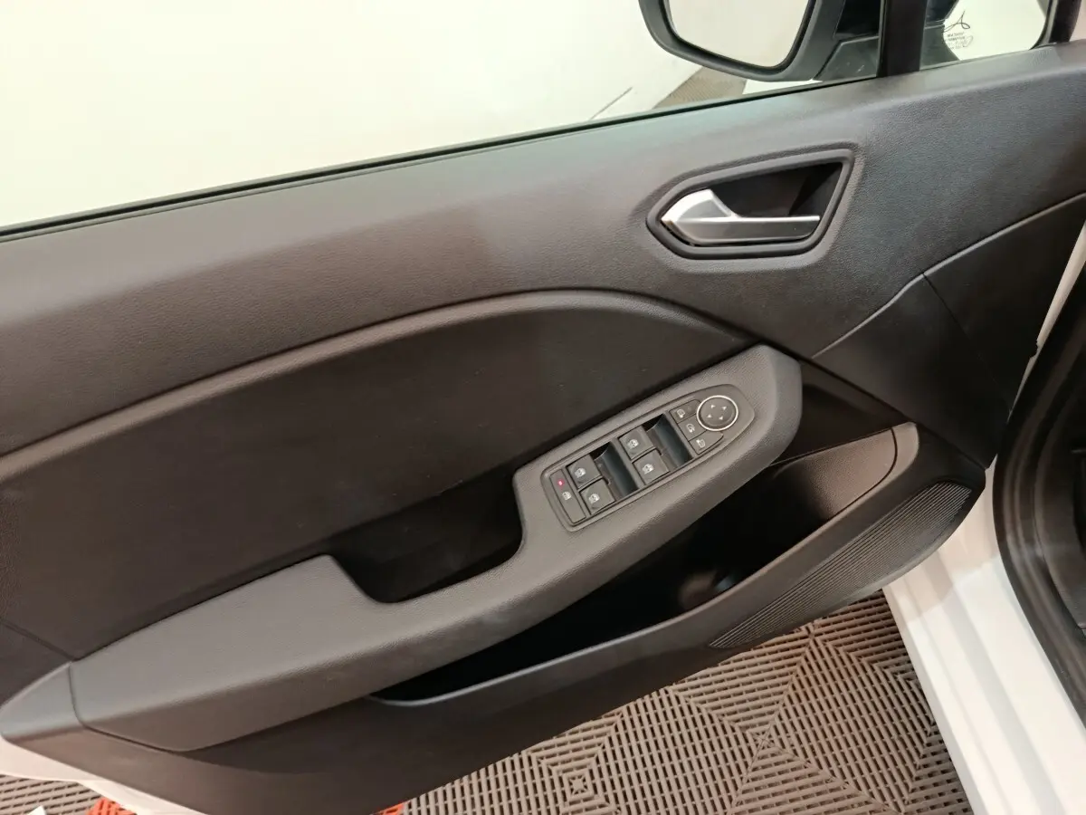 Vue intérieure du panneau de porte avant gauche de la Renault Clio blanche, avec commandes électriques des vitres et rétroviseurs.