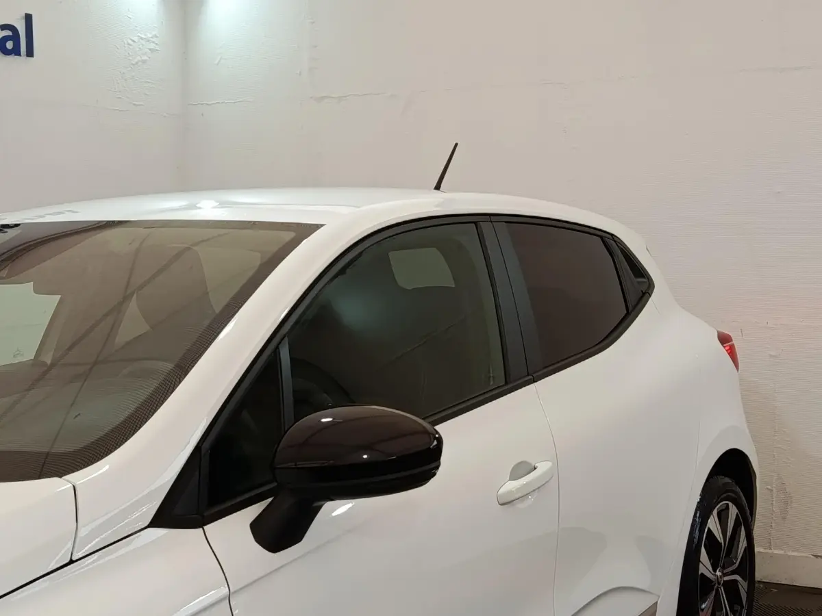 Vue latérale droite d'une Renault Clio Evolution TCe 90 blanche avec rétroviseur noir et vitres teintées.