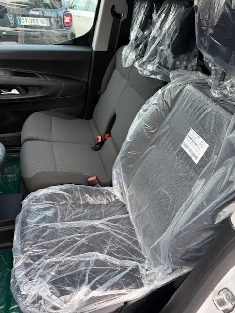 Vue intérieure côté droit du Citroën Berlingo 2026, sièges avant protégés par des housses plastiques transparentes.