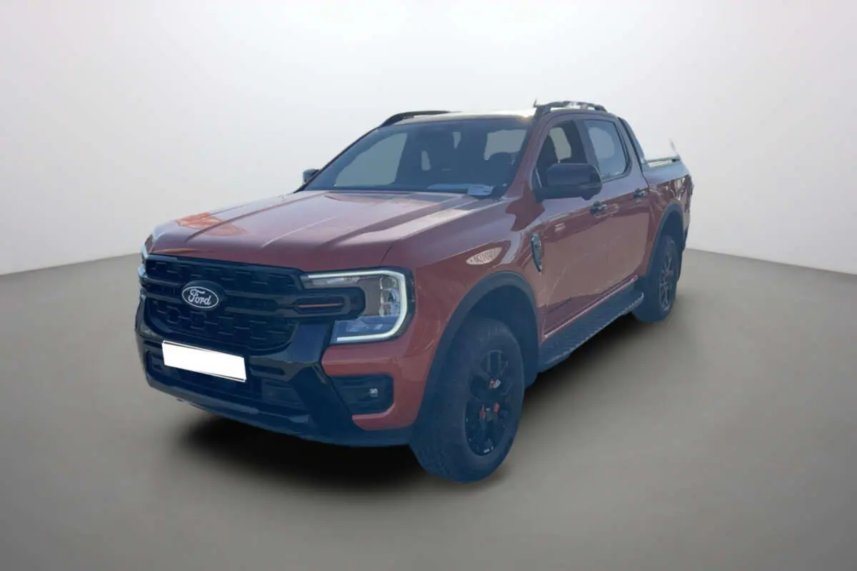 Ford Ranger Wildtrak orange Ignite vu en 3/4 avant droit avec jantes noires et barres de toit.