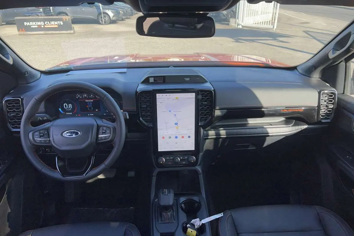 Vue intérieure avant du Ford Ranger Wildtrak Plus 2026 avec tableau de bord noir, écran tactile vertical et volant multifonctions.