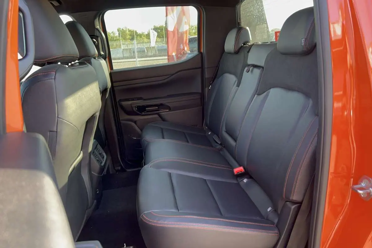 Vue intérieure arrière côté droit du Ford Ranger Wildtrak 2026 orange, sièges cuir noirs avec surpiqûres orange.