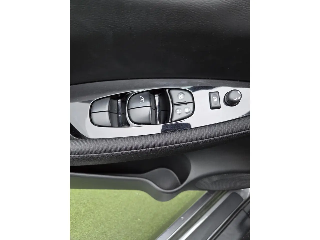 Gros plan sur les commandes de lève-vitres et rétroviseurs côté conducteur du Nissan Leaf gris foncé 2021.