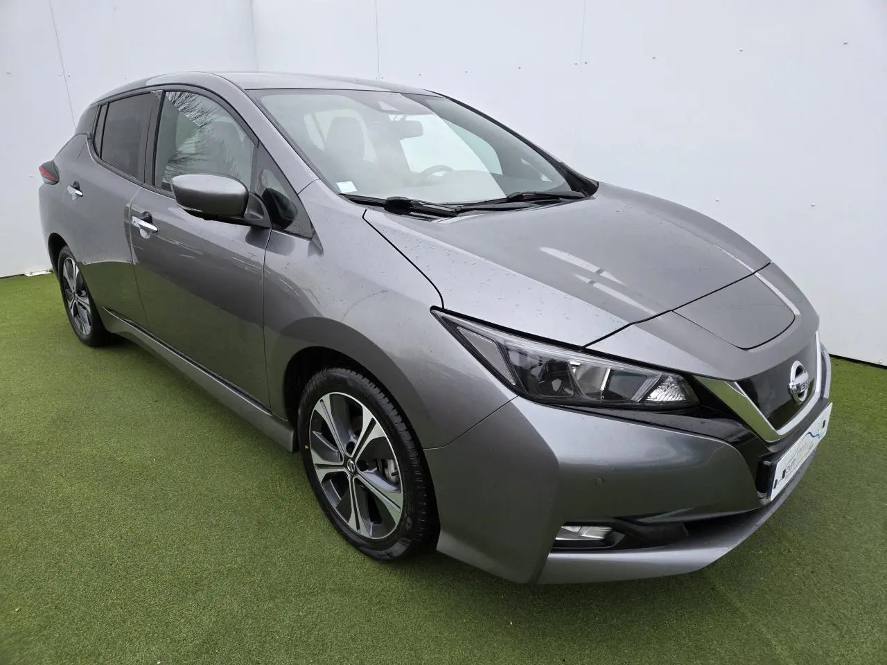 Nissan Leaf II gris foncé métallisé vue 3/4 avant droit sur sol vert avec phares LED et jantes alliage.