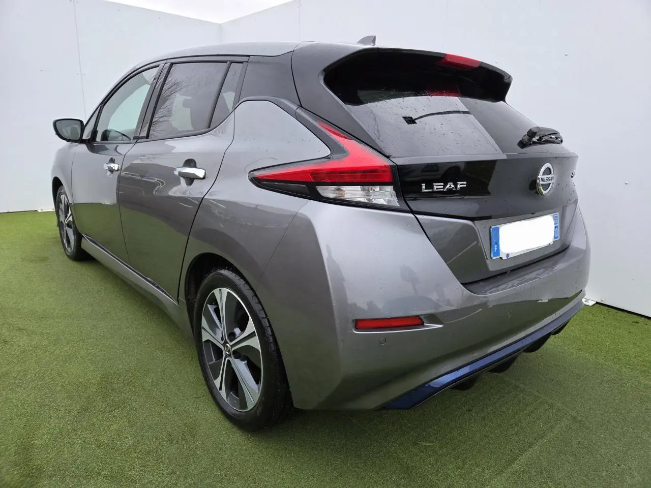 Vue 3/4 arrière droite d'une Nissan Leaf II gris foncé métallisé avec feux arrière LED et jantes alliage.