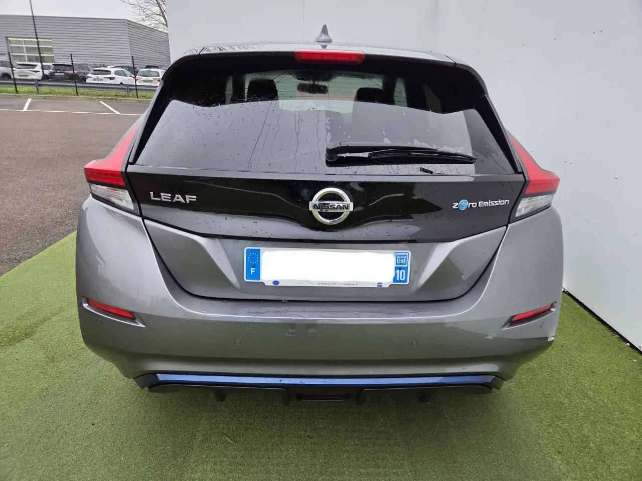 Vue arrière d'une Nissan Leaf II gris foncé métallisé avec logo Zero Emission et feux arrière LED distinctifs.