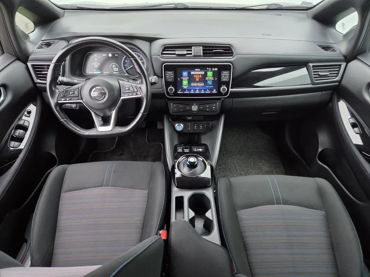Vue intérieure avant du Nissan Leaf II gris foncé, avec tableau de bord numérique et volant cuir multifonction.