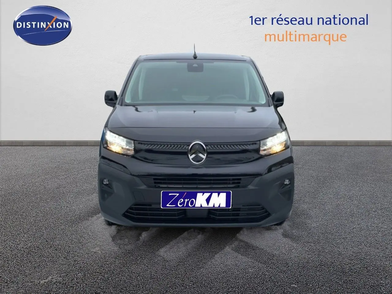 Vue frontale d'un Citroën Berlingo Van XL noir Perla Metal avec phares allumés sur sol goudronné.