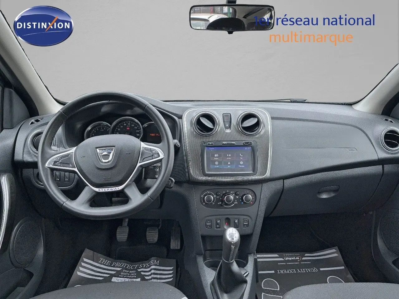 Vue intérieure frontale du tableau de bord gris foncé du Dacia Sandero Stepway 2016 avec volant multifonction et écran central tactile.