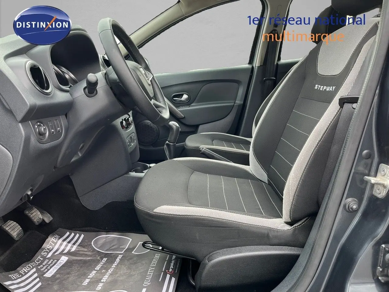 Vue intérieure côté conducteur de la Dacia Sandero Stepway 2016 gris foncé, sièges avec logo Stepway visibles.