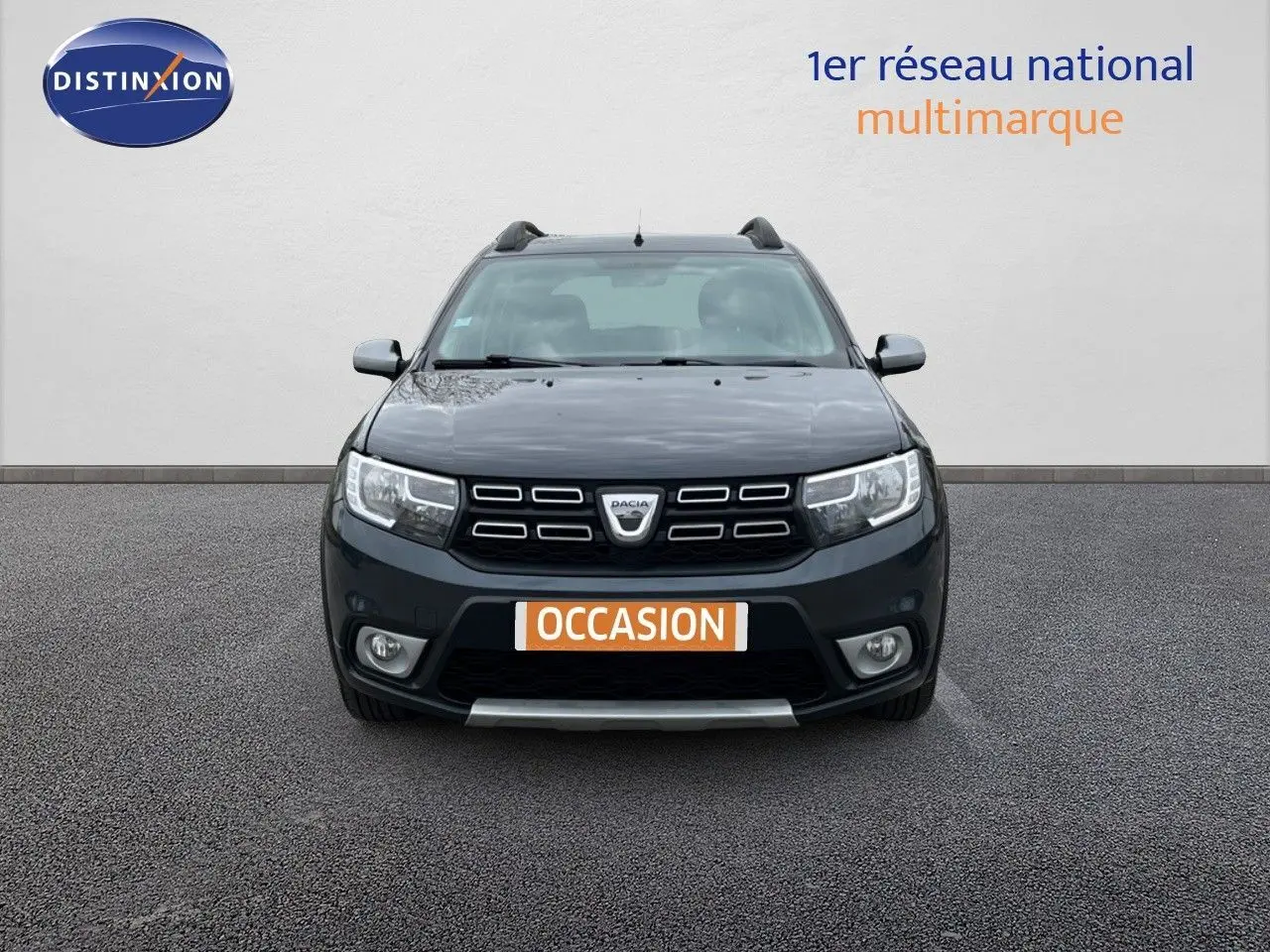 Vue de face d'une Dacia Sandero Stepway gris foncé 2016 avec calandre noire et plaques "OCCASION" visibles.