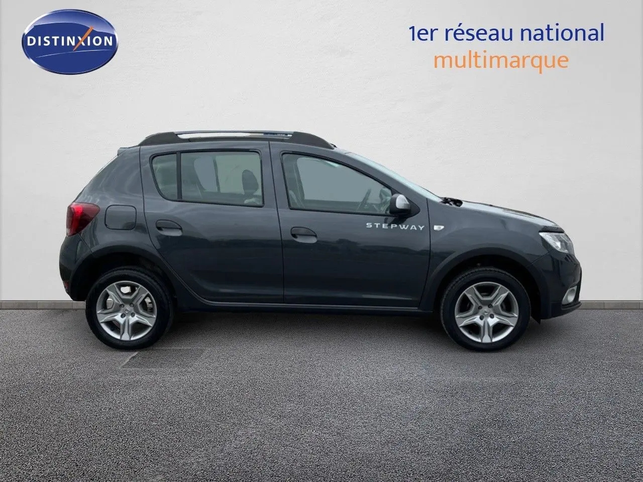 Vue de profil côté gauche d'une Dacia Sandero Stepway gris foncé de 2016 avec jantes alliage et badge Stepway visible.