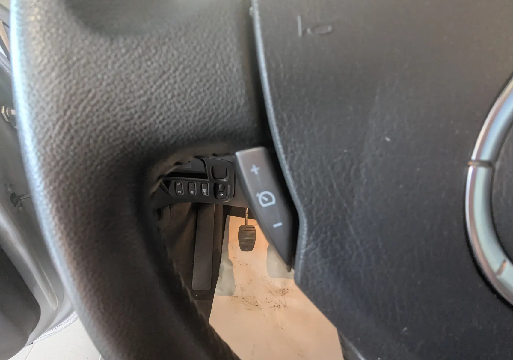 Gros plan sur le volant en cuir noir du Renault Grand Espace IV, montrant les commandes de régulateur de vitesse côté gauche.