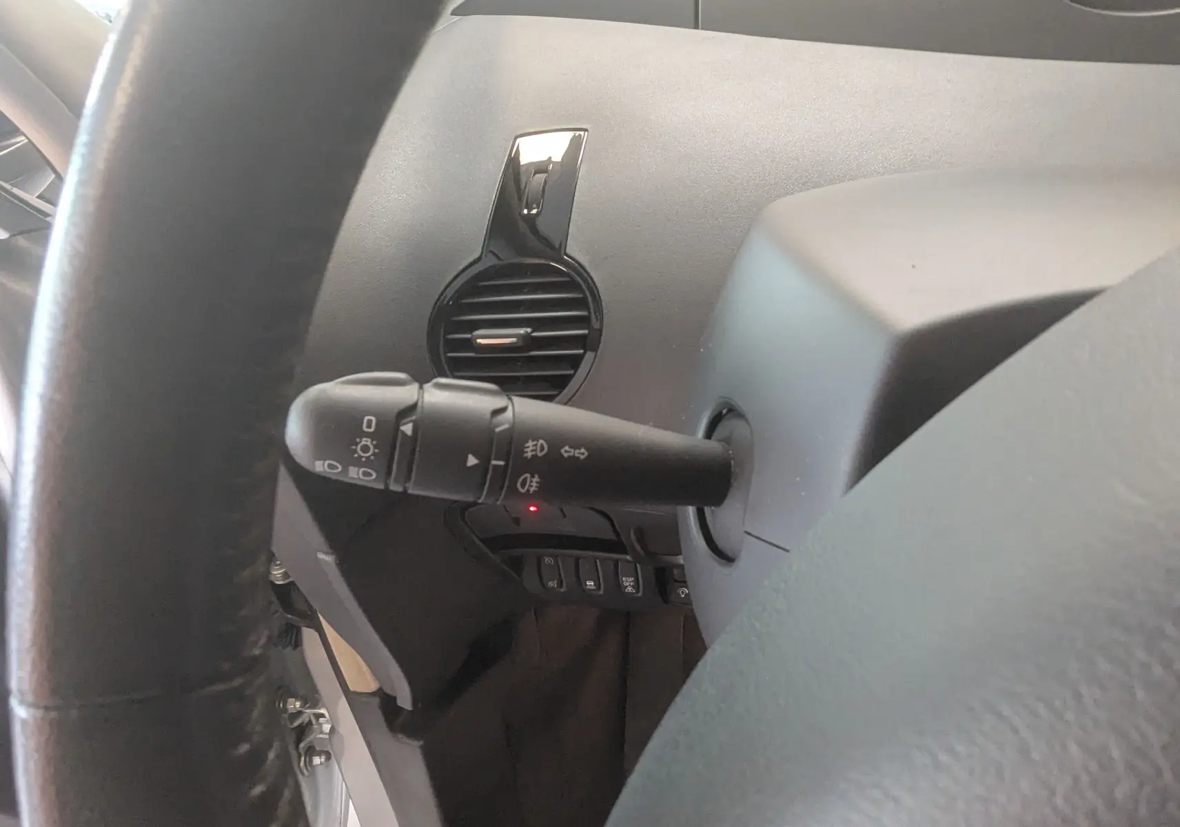 Gros plan sur la manette de commandes d'éclairage à gauche du volant dans l'habitacle noir du Renault Grand Espace IV gris clair.