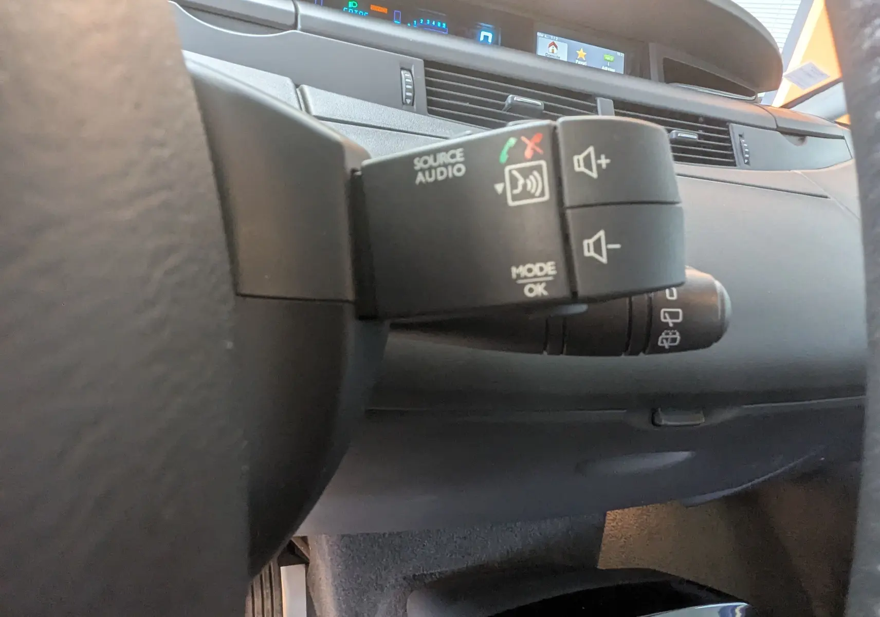 Gros plan sur la commande audio au volant du Renault Grand Espace IV gris clair, avec tableau de bord et écran numérique en arrière-plan.