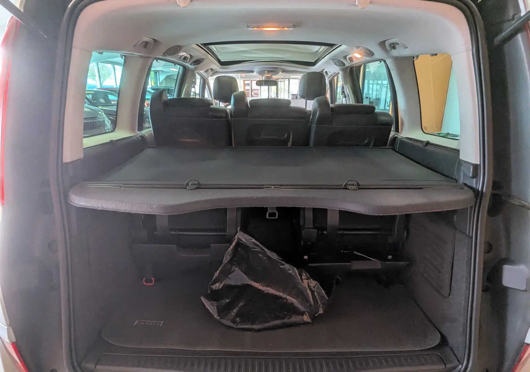 Vue arrière ouverte du coffre du Renault Grand Espace IV gris clair, avec cache-bagages et sièges noirs visibles.