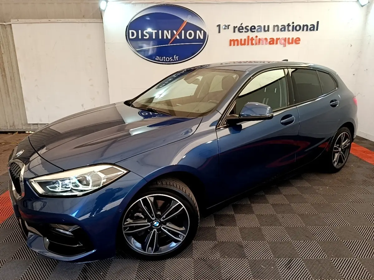 BMW Série 1 118i Edition Sport bleu vue 3/4 avant droit, avec phares LED et jantes alliage noires.