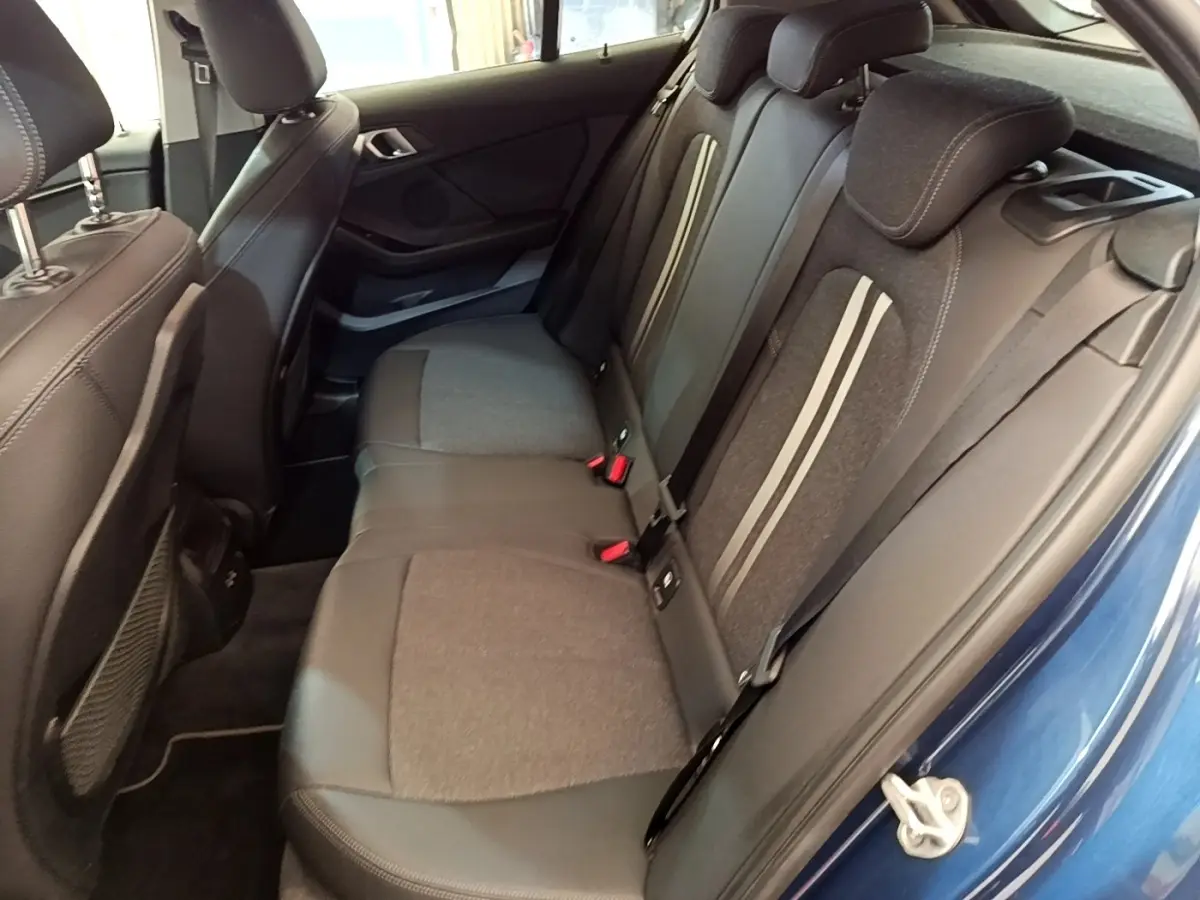 Vue intérieure côté arrière droit de la banquette tissu et cuir gris foncé d’une BMW Série 1 bleu 118i Edition Sport 2023.