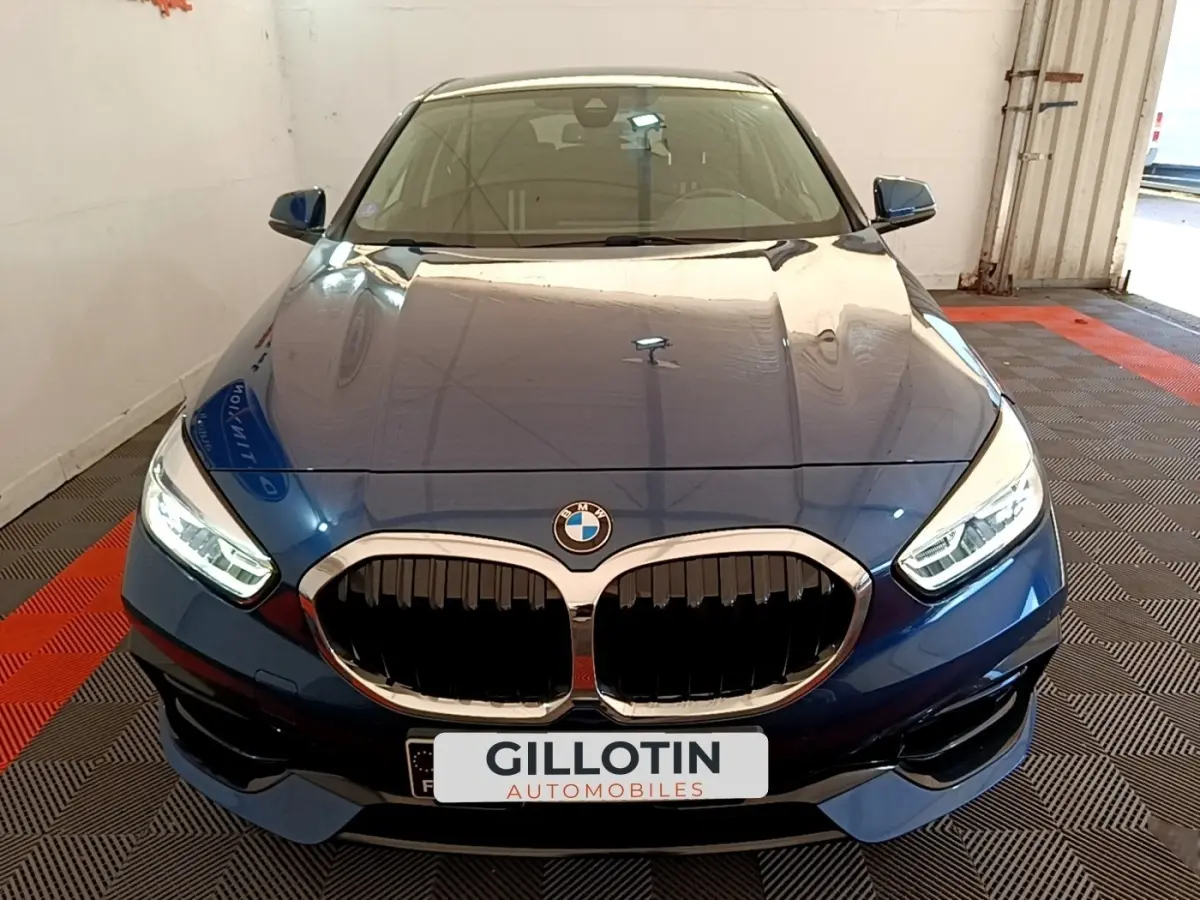 Vue avant rapprochée d’une BMW Série 1 118i Edition Sport bleu avec calandre double haricot et phares LED allumés.