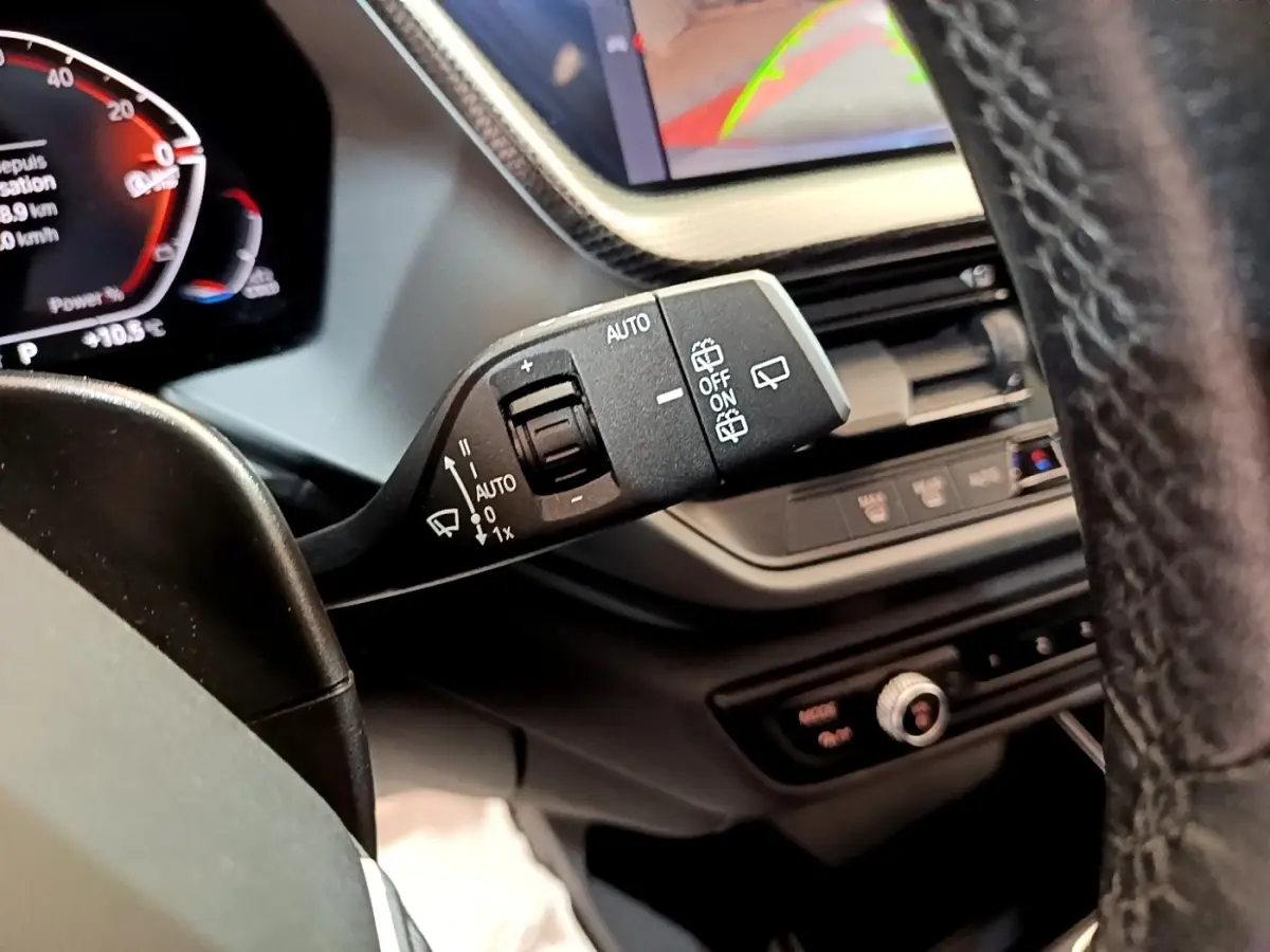 Gros plan sur la commande d’essuie-glace à gauche du volant dans l’habitacle de la BMW Série 1 bleu 118i Edition Sport 2023.