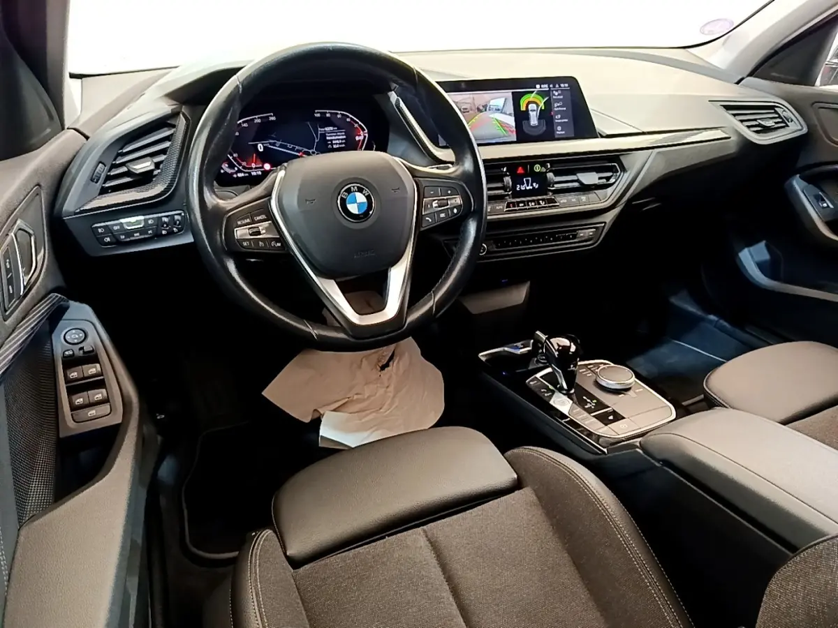Vue intérieure de la BMW Série 1 118i Edition Sport 2023, tableau de bord et console centrale avec écran tactile couleur.