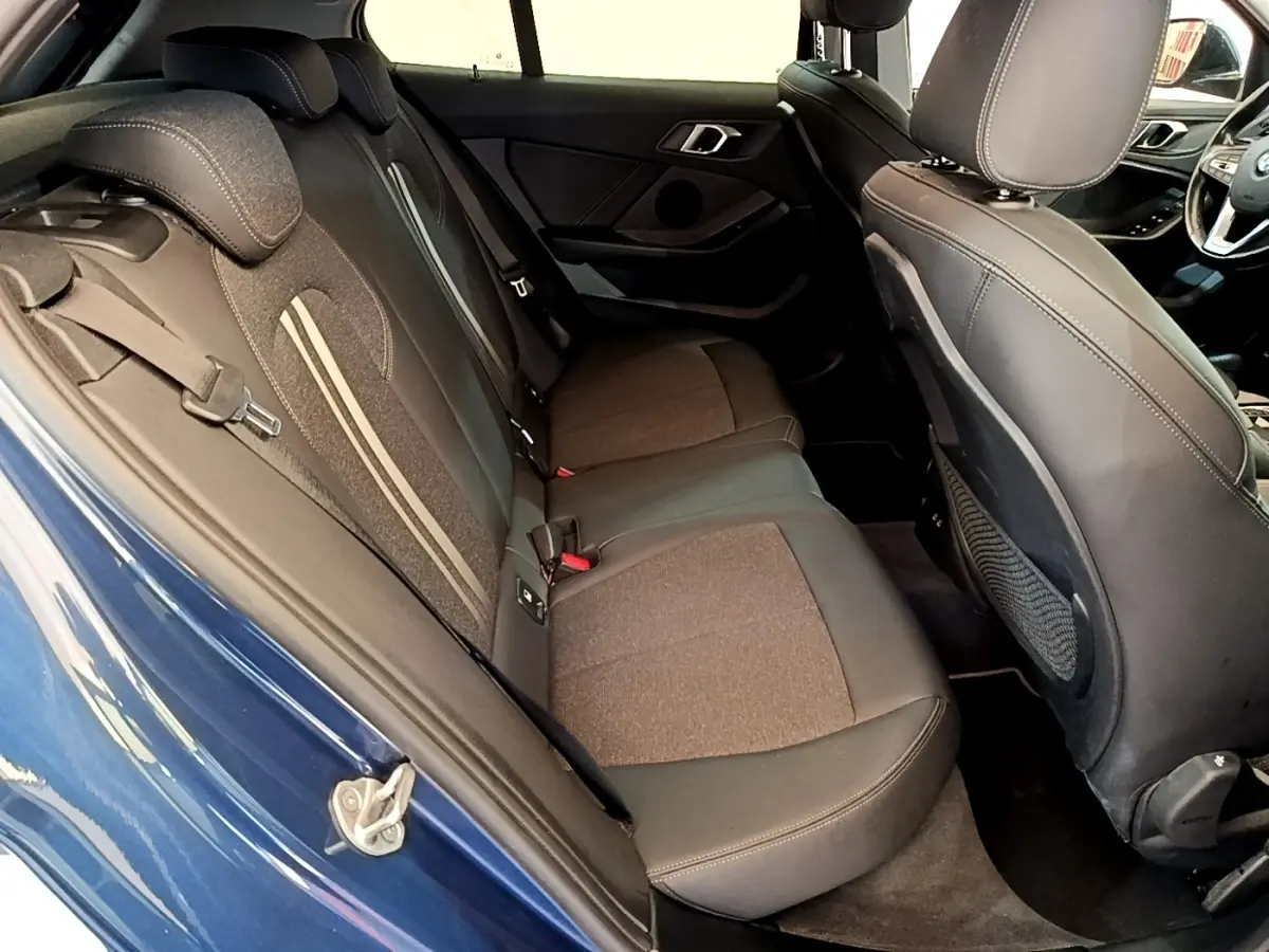 Vue intérieure côté arrière gauche de la BMW Série 1 118i Edition Sport bleu, montrant la banquette arrière et les sièges avant.