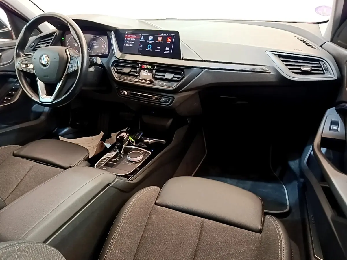 Vue intérieure côté conducteur de la BMW Série 1 118i Edition Sport 2023 avec tableau de bord et écran tactile.