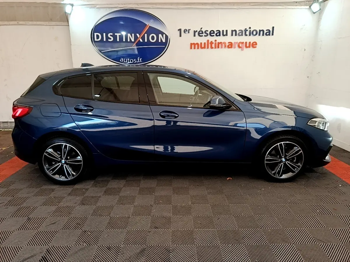 Profil droit d'une BMW Série 1 118i Edition Sport bleu métallisé, avec jantes alliage et vitres teintées.