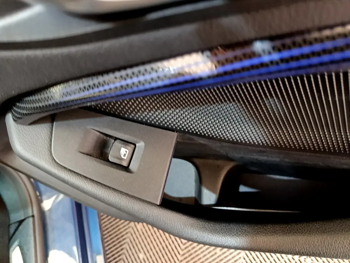 Gros plan sur le bouton de commande de la vitre électrique côté conducteur, intérieur bleu et noir de la BMW Série 1 118i Edition Sport.